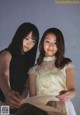 A couple of women standing next to each other holding a book.