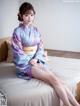 A woman in a kimono sitting on a bed.