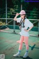 A woman in a white shirt and pink tights standing on a tennis court.