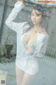 A woman in a white shirt is posing in the rain.