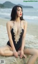 A woman sitting on a rock on the beach.