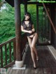 A woman in a black lingerie posing on a porch.